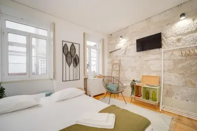 a bedroom with two beds and a tv on a stone wall at Nomad's Bonjardim City Flats in Porto