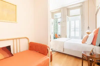 a bedroom with two beds and a chair and a window at Get a Golden and Flower Flat in Porto