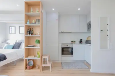 a room with a bed and a kitchen with white cabinets at Liiiving in Porto I Bright Light Studio in Porto