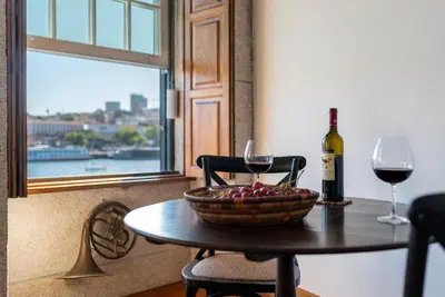 a table with a bowl of fruit and a bottle of wine at Porto Premium River View I in Porto