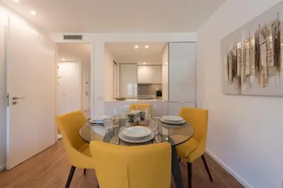 a dining room with a glass table and yellow chairs at LovelyStay - Downtown Balcony Apartment with Free Parking in Porto