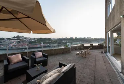 a patio with couches and an umbrella on a building at Villa D'Ouro in Porto