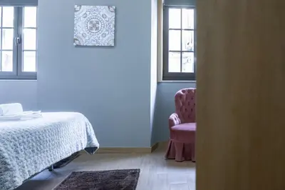 a bedroom with a bed and a chair next to a window at D'OURO DOM MANUEL By LW in Vila Nova de Gaia