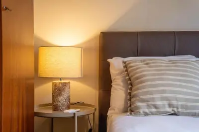 a lamp on a side table next to a bed at Firmeza388 Charming Flats - Comfort & Privacy with 2 Bedrooms in Porto