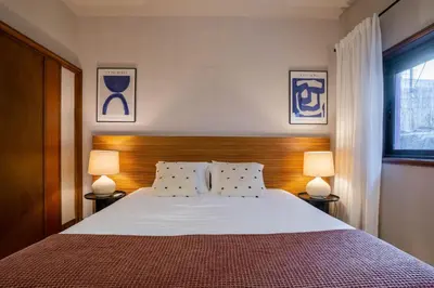 a bedroom with a large bed with two lamps at Firmeza388 Charming Flats - Comfort & Privacy with 2 Bedrooms in Porto