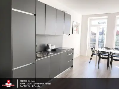 a kitchen with white cabinets and a table with chairs at Downtown Fantail in Porto
