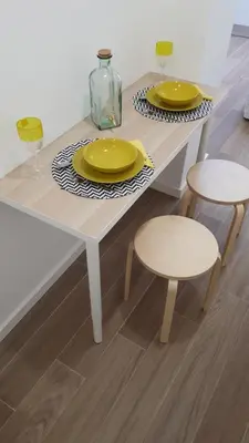 a white table with two yellow plates and two stools at TMB (Train / Metro& Bus ) Oporto Station House in Porto