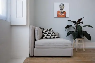 a gray chair in a living room with a plant at Baixa24 •P2R• Bright Apt in Vibrant Downtown in Porto