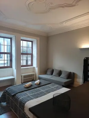a bedroom with a bed and a couch and windows at Baixa24 •P1R• Brand New Apt in the Historic Center in Porto
