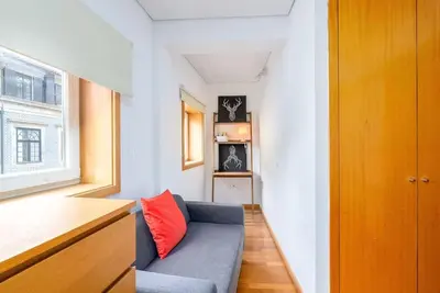 a small living room with a blue couch and a window at Cedofeita Paradise w parking included in Porto