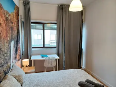 a bedroom with a bed and a desk and a window at Oporto Cozy Rooms in Porto
