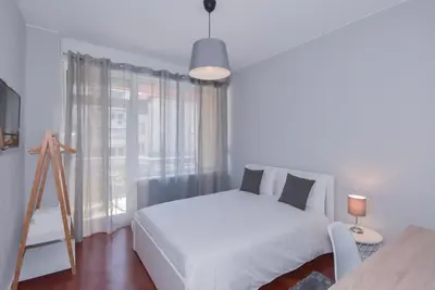 a white bedroom with a white bed and a window at Lolla's City House in Porto