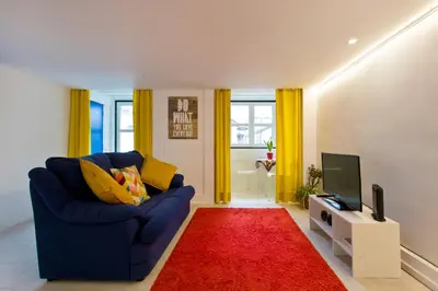a living room with a blue couch and a red rug at Oporto Blue Trindade - Magical Citycenter Apartment in Porto