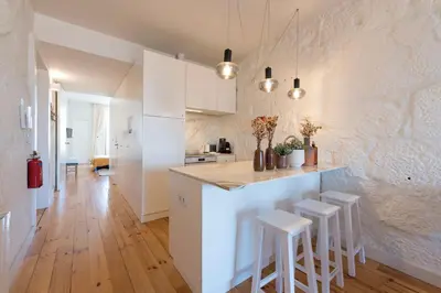 a kitchen with white cabinets and a counter with stools at Cativo Apartment - Porto Downtown in Porto