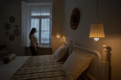 a woman standing in a bedroom looking out the window at Domus Duorum in Porto