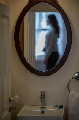a woman standing in front of a mirror over a bathroom sink at Domus Duorum in Porto