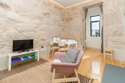 a living room with a tv and a chair and a table at GuestReady - Charming Downtown and Quiet Apartment in Porto