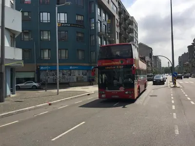 a red double decker bus driving down a city street at Invicta House Loft Boavista in Porto