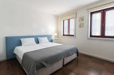 a bedroom with a bed with a blue headboard and two windows at Porto Gaia City House by MP in Vila Nova de Gaia