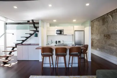 a kitchen and living room with a bar with stools at D'Autor Apartments Alegria in Porto