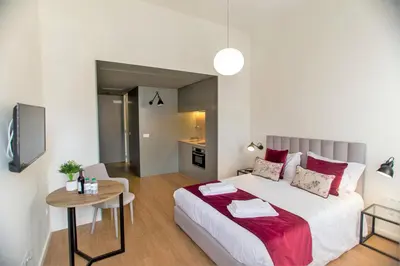 a bedroom with a large bed and a table at Clérigos Prime Suites by Porto City Hosts in Porto