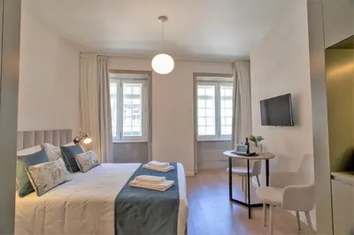 a bedroom with a bed and a table with a chair at Clérigos Prime Suites by Porto City Hosts in Porto