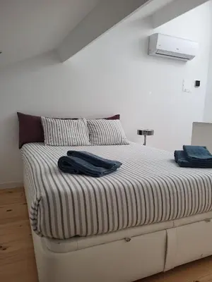 a bed in a white room with two towels on it at New Bluebell house in heart of Porto in Porto