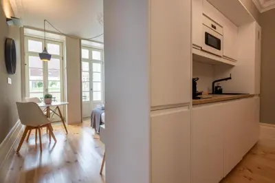a kitchen with white cabinets and a table in a room at MyStay Porto - Urban Collection in Porto