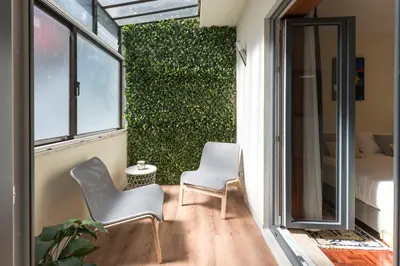a balcony with two chairs and a green hedge at LovelyStay - Heritage Collection House with 4Bedrooms in Porto