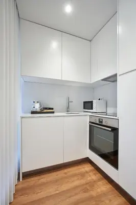 a white kitchen with white cabinets and a microwave at Signature Apartments Santa Catarina in Porto