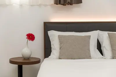 a bed with a vase with a red flower on a table at Bra.com Apartments Oporto Faria Guimarães in Porto