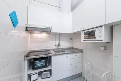 a small kitchen with white cabinets and a microwave at GuestReady - Music Flats 2 in Porto