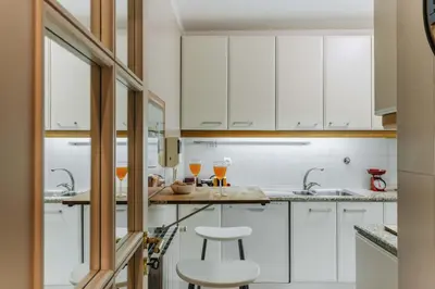 a kitchen with white cabinets and two glasses of wine at Spacious 1BR with Parking in Quiet Area in Vila Nova de Gaia