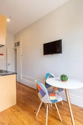 a table and chairs in a kitchen with a tv on a wall at ZD Moreira Flats B By PortoProperties4You in Porto