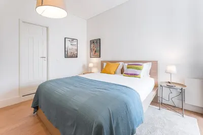 a white bedroom with a large bed with colorful pillows at GuestReady - Costa Cabral Guesthouse in Porto