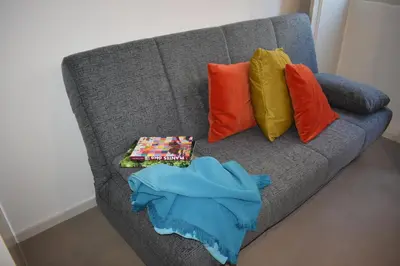 a gray couch with colorful pillows and a blanket on it at Casa Barão Forrester in Porto