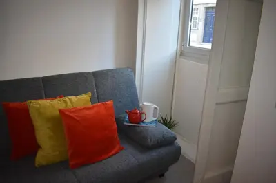 a gray couch with orange and yellow pillows and a mug at Casa Barão Forrester in Porto