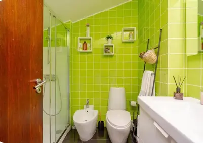 a green tiled bathroom with a toilet and a sink at Terraço da Boavista in Porto