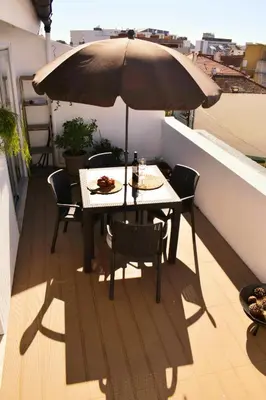 a table and chairs with an umbrella on a balcony at Terraço da Boavista in Porto