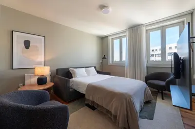 a bedroom with a bed and two chairs and a television at Cedofeita Deluxe Apartment 3B in Porto