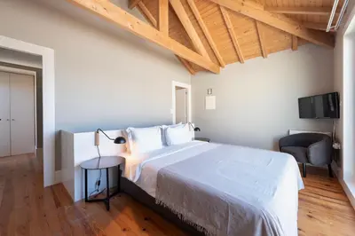 a bedroom with a large bed and a chair at Cedofeita Deluxe Apartment 3B in Porto