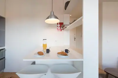 a white kitchen with two stools and two plates of food at LovelyStay - Gorgeous Modern Flat w/ Balcony in Porto