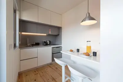 a kitchen with white cabinets and a table and a chair at LovelyStay - Gorgeous Modern Flat w/ Balcony in Porto