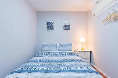 a white bedroom with a bed and a lamp at Apartamento Lar doce Lar Porto in Vila Nova de Gaia