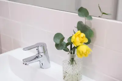 a vase with yellow flowers sitting on a bathroom sink at Porto Belo Sao Bento Apartment in Porto