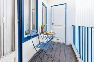 a small table and a blue chair on a balcony at Porto Belo Sao Bento Apartment in Porto