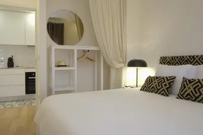 a white bedroom with a large bed and a mirror at Oporto Wall Apartments in Porto