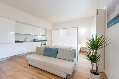 a living room with a white couch and a kitchen at GuestReady - Bay Watch in Porto