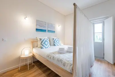 a white bedroom with a bed and a window at GuestReady - Bay Watch in Porto