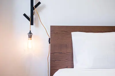 a light hanging from a wall next to a bed at GuestReady - Grit & Glam in Porto
